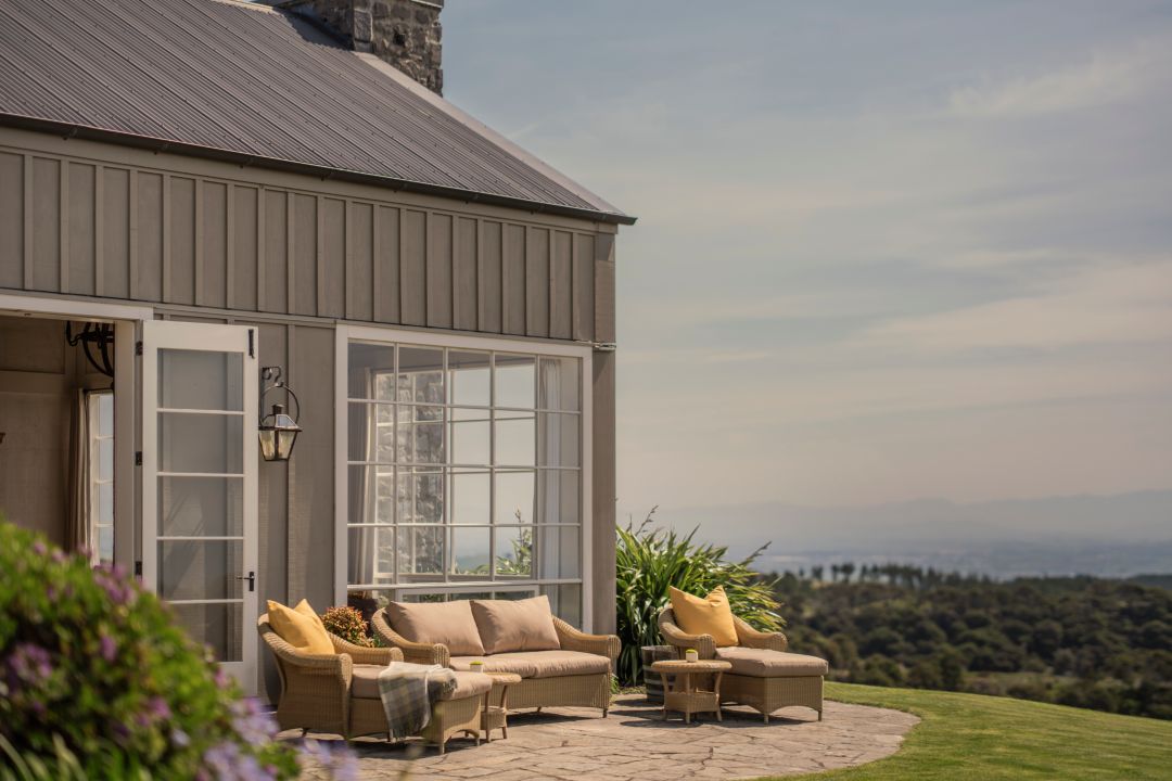 Stone terrace outside a luxury villa with level lawn and views overlooking the Hawke’s Bay. 